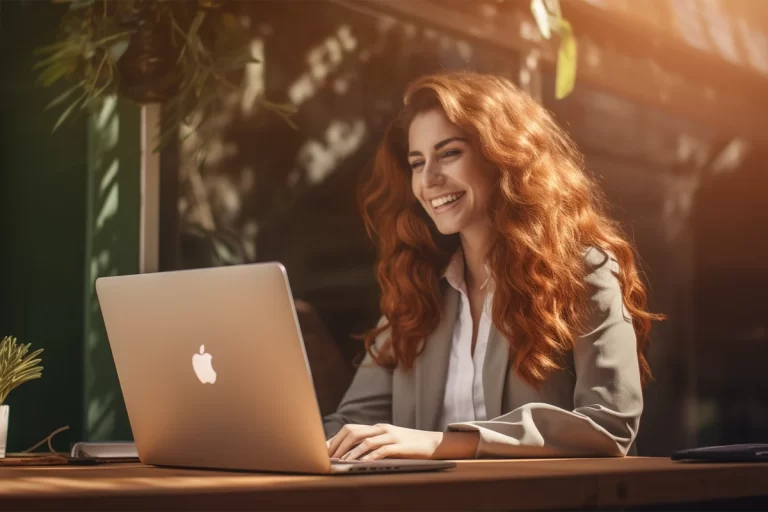 Femme souriante travaillant sur un MacBook.