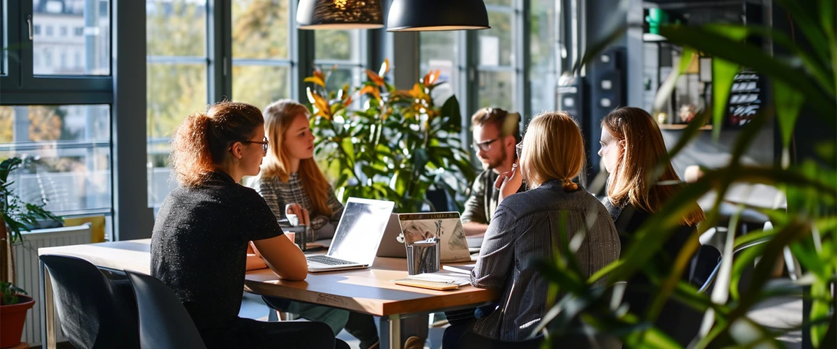 Photo d'une réunion de travail avec quatre personnes assises autour d'une table qui discute de comment Aller à la ligne dans une cellule Excel